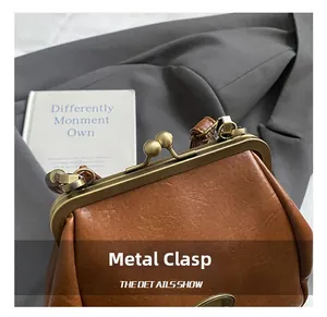 Gros plan du fermoir en métal bronze vintage sur le sac coquille en cuir marron