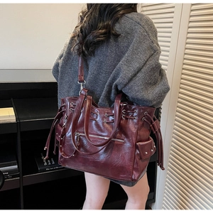 Vue détaillée du grand sac cabas bordeaux avec rivets et poche latérale à cordon