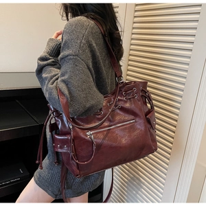 Gros plan sur un sac cabas bordeaux avec rivets argentés et texture en cuir plissé