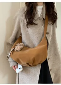 Détail d'un sac demi-lune en daim marron avec pendentif ours en peluche et base plissée souple