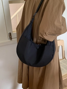 Modern black nylon crescent shoulder bag with quilted texture shown on a female model