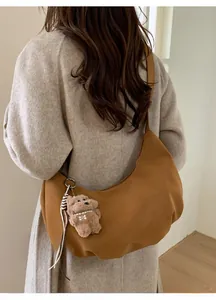 Détail du sac croissant en daim marron avec pendentif ours en peluche et bandoulière