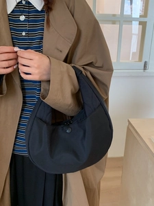Minimalist black quilted crescent tote bag shown in a stylish lifestyle setting for women