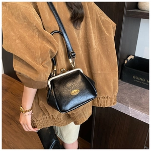 Détail du sac rétro noir avec plaque dorée handmade et texture brillante chic