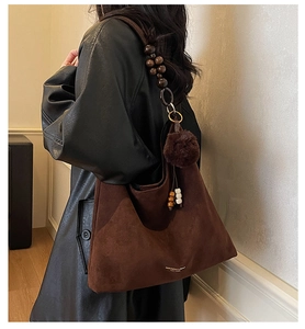 Detail of vintage brown suede tote bag with decorative dark wooden bead shoulder strap