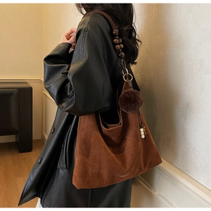 Detail of caramel suede tote bag featuring unique dark brown wooden bead shoulder strap