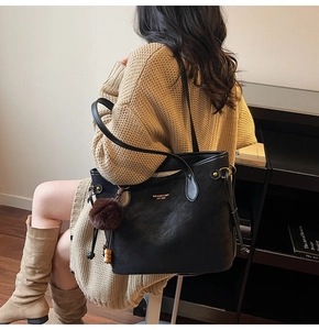 Detail of black matte PU leather tote bag with gold logo and fluffy fur ball charm