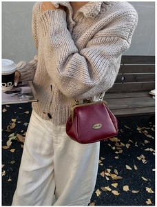 Détail du sac vintage bordeaux montrant la texture du cuir et le logo en métal en automne