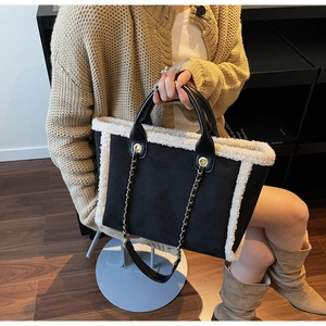 Detail of suede tote bag with white faux fur trim and elegant metal chain strap