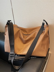 Japanese style brown grid tote bag with adjustable black strap on a leather sofa