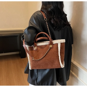 Macro shot of brown suede tote bag featuring white faux shearling trim and gold metal chain