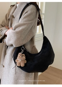 Sac hobo minimaliste en daim noir porté épaule avec charmant pendentif chien peluche