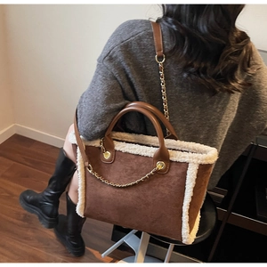 Close-up of brown suede tote bag featuring white faux fur trim and gold chain detail