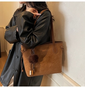 Macro view of brown suede tote bag with plush ball charm and MIAOXI brand stamp