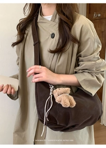 Détail du sac bandoulière demi-lune marron foncé avec un petit ours en peluche