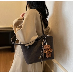 Detail of dark brown faux suede tote bag with plush bear charm and contrast stitching