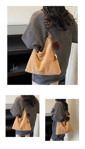 Detail of tan suede hobo bag featuring a wooden bead strap and pom-pom charm detail
