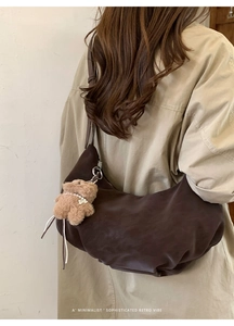 Détail du grand sac croissant marron en simili cuir avec un pendentif ours peluche