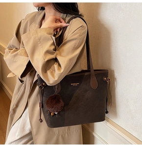 Detail of dark brown faux suede tote bag with gold logo lettering and plush charm