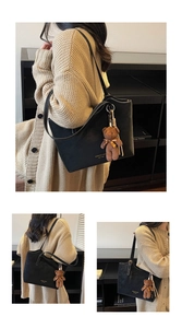 Detail of matte black tote bag featuring a cute brown plush bear charm and gold lettering