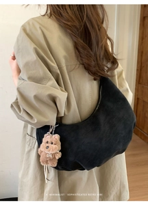 Détail d'un sac hobo noir avec pendentif ours en peluche et une ambiance rétro minimaliste
