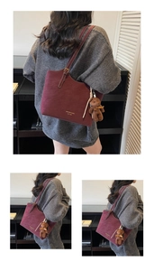 Close-up of burgundy tote bag with gold lettering and a cute brown plush bear charm