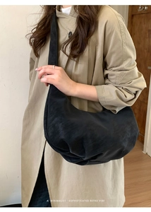 Sac hobo noir en daim porté avec un manteau kaki pour un style minimaliste et chic