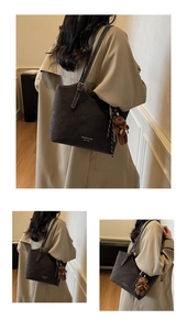 Detail of dark brown tote bag with adjustable straps and a cute plush bear charm decoration
