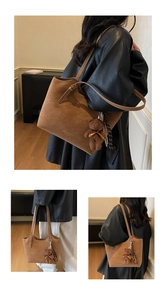 Detail of a brown suede tote bag with a cute bear charm and striped scarf decoration