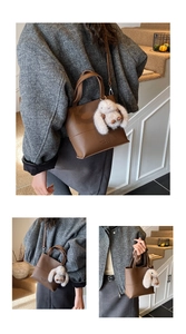 Detail of brown litchi pattern leather bag with detachable strap and plush rabbit charm