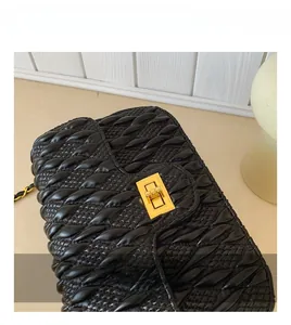 Detailed close-up of premium golden metal twist lock on black quilted leather handbag