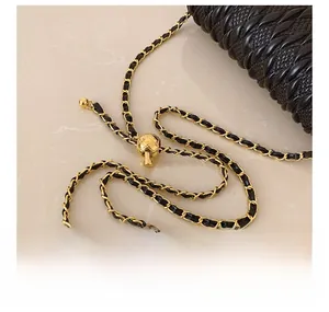 Detailed close-up of the black woven leather bag with gold chain and sphere adjuster