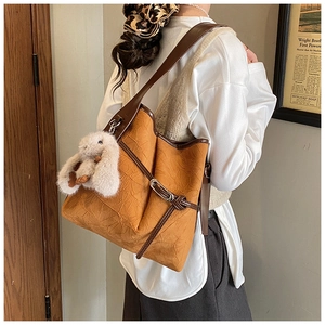 Detail of vintage caramel tote bag with wrinkled leather texture and cute bunny charm