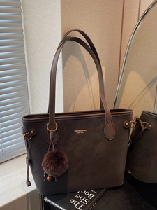 Dark taupe minimalist tote bag with thin brown straps and plush ball charm in soft light