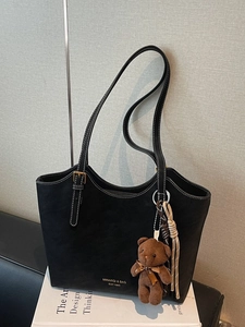 Minimalist black tote bag in matte synthetic leather with contrast stitching and bear charm
