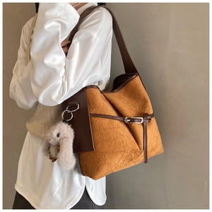 Detail of vintage tote bag in textured orange-brown material with plush rabbit charm