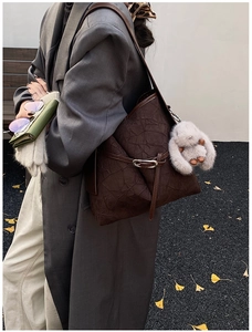 Detail view of large brown vintage tote bag featuring a white plush rabbit pendant