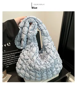 Detalle del bolso acolchado azul claro con costuras romboidales y cierre de cremallera