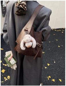 Detail of retro brown pleated tote bag featuring wide shoulder strap and plush rabbit charm
