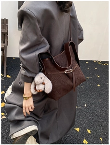 Detail of dark brown tote bag with pleated texture and plush rabbit charm in autumn setting