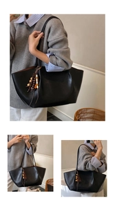 Detail of black leather tote bag with unique multicolor wooden bead tassel pendant