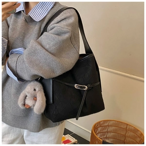 Detail of black pleated tote bag with silver buckle and gray bunny plush charm