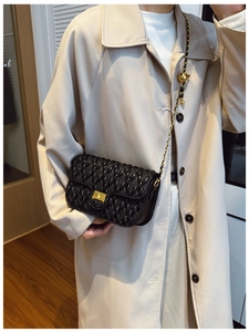 Detail of black woven quilted bag with gold rotating lock and adjustable chain ball