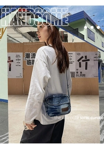 Street style view of washed denim crossbody bag with vintage worn-out finish and brown label