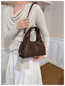Detail of dark brown lychee leather handbag with pleated design on a white sweater