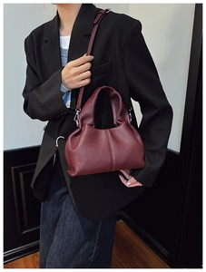 Close-up of deep red lychee grain leather bag with soft pleats and metal buckle detail