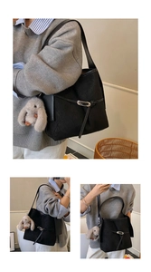 Detail of black textured bucket bag with silver buckle and plush bunny charm