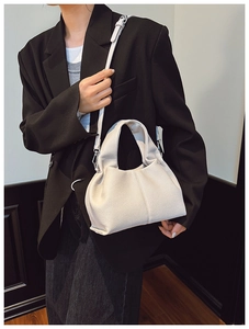 Close-up of cream pleated leather dumpling bag with detachable shoulder strap details