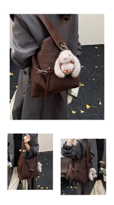 Detail of dark brown tote bag with pleated texture and plush rabbit charm in outdoor setting