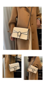 Detail of off-white crossbody bag with leopard print, tiger buckle, and metal chain
